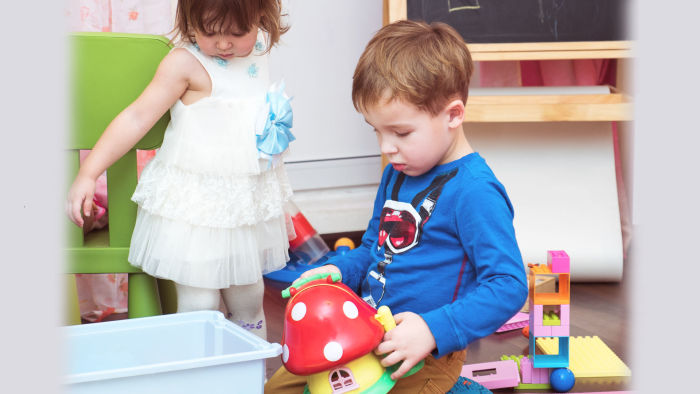 Little boy and girl cleaning up their toys