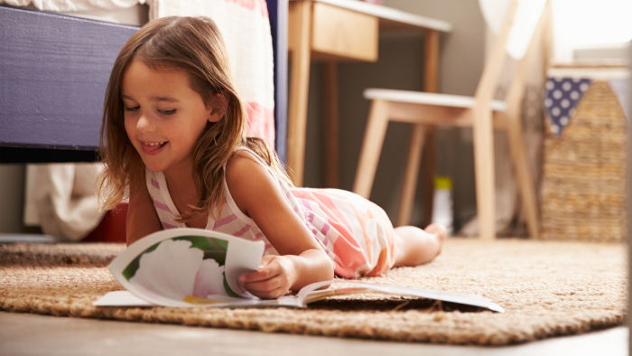 Little girl reading book on floor
