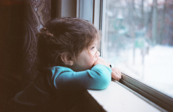 Little girl staring out of window