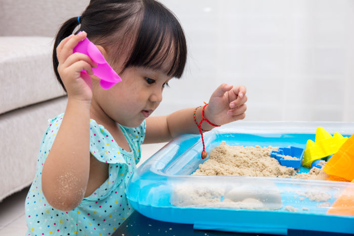 Little Asian girl playing with sand