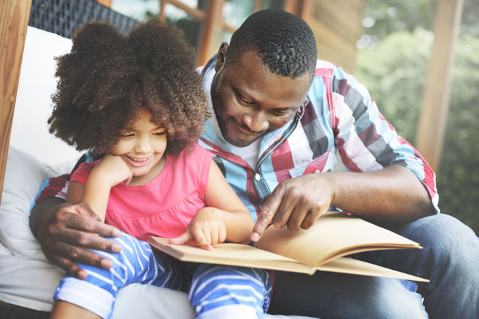 African American father and daughter reading book together