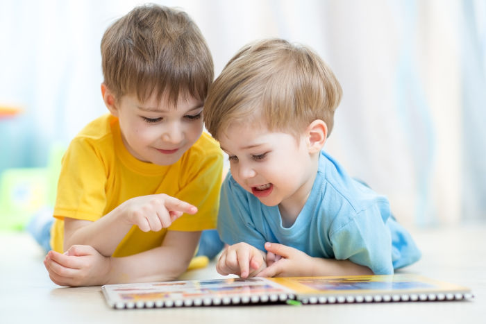 Two little brothers practicing reading a book