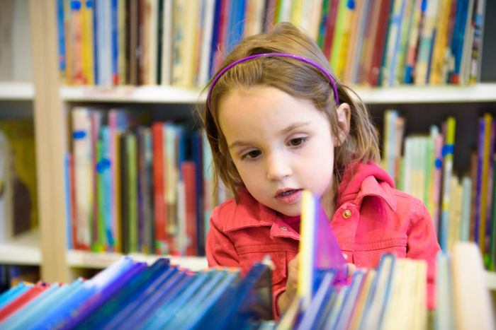 Little girl looking through library books