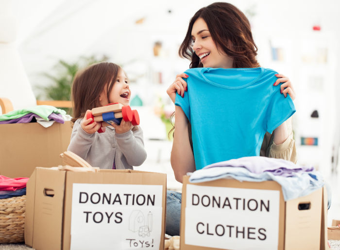 Little girl and mother placing toys and clothes in donation boxes