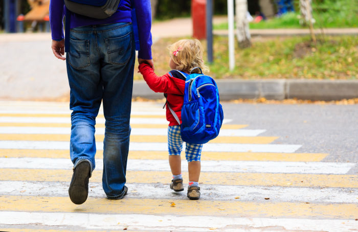 Little girl crossing street while holding father's hand