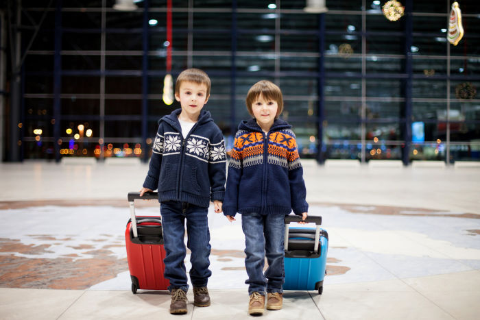 Two little boys pulling suitcases in an airport