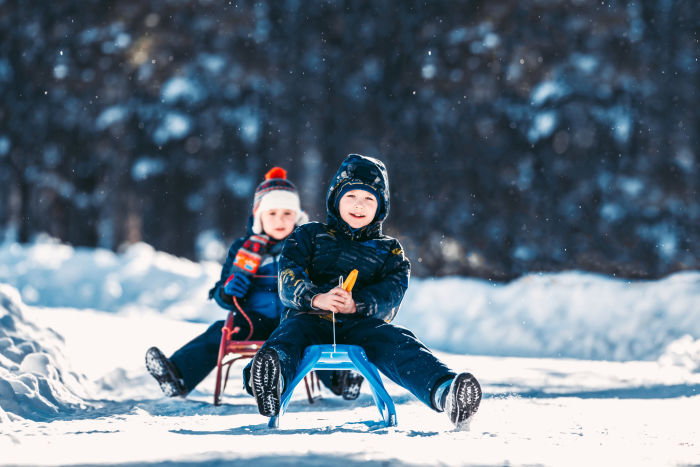2 boys sledding in snow