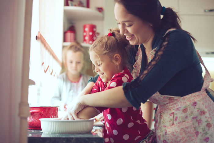 2 little girls cooking with their mother