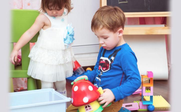 Little boy and girl cleaning up their toys