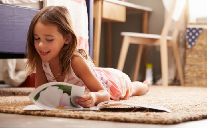 Little girl reading book on floor