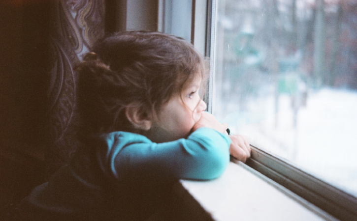 Little girl staring out of window