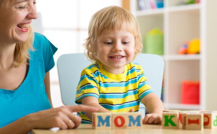 Little boy and his mother playing with letter blocks