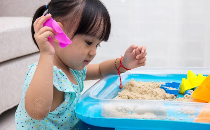 Little Asian girl playing with sand