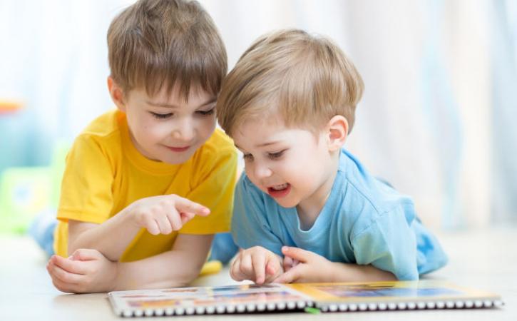 Two little brothers practicing reading a book