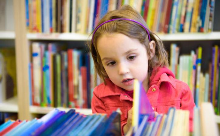 Little girl looking through library books