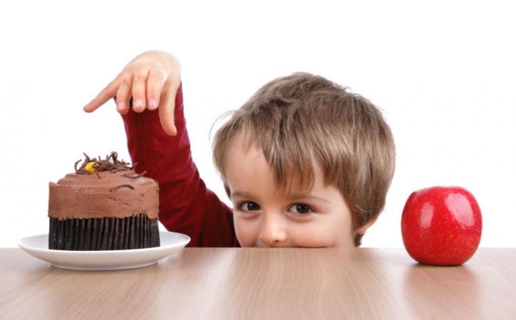 Little boy deciding between apple and cupcake