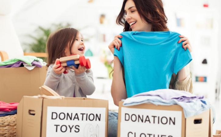 Little girl and mother placing toys and clothes in donation boxes