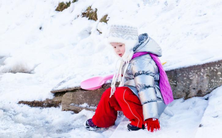 Little girl in snow with pink shovel