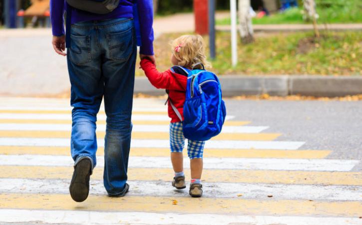 Little girl crossing street while holding father's hand