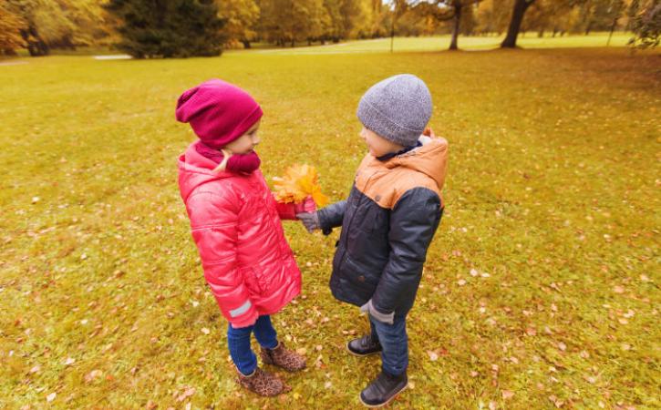 Little boy handing little girl bouquet of leaves