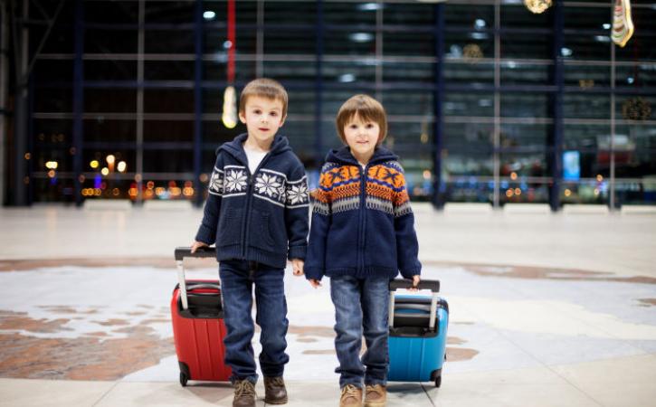 Two little boys pulling suitcases in an airport