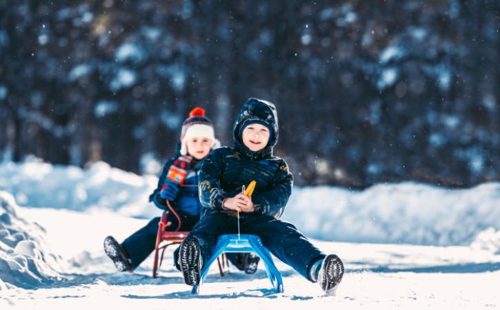 2 boys sledding in snow