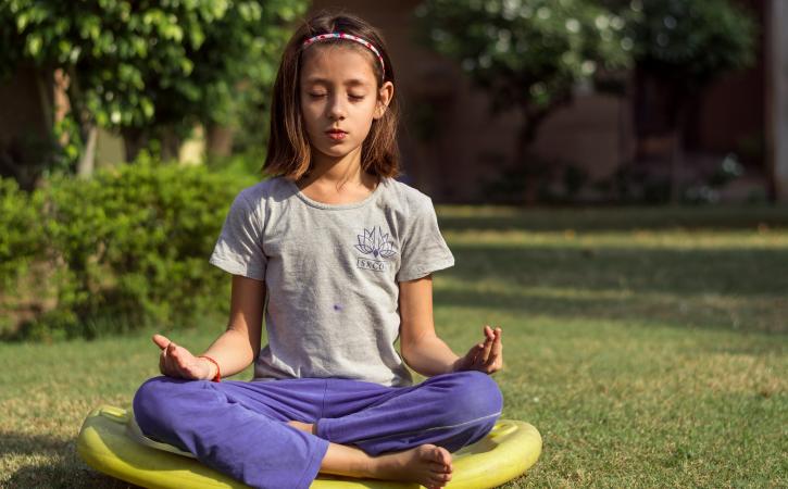 Teaching kids mindfulness - young girl meditating