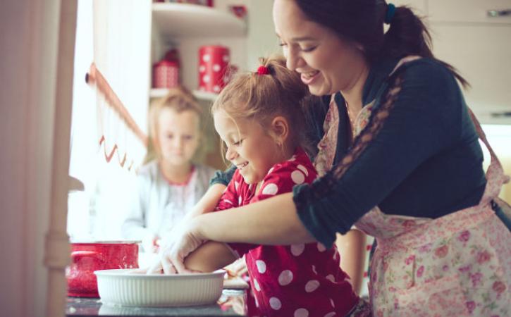 2 little girls cooking with their mother
